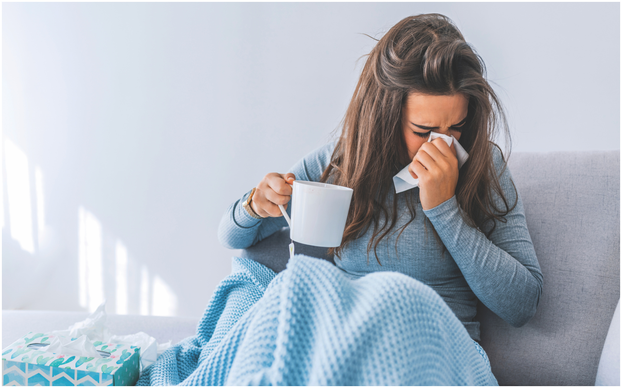 Woman sneezing into tissue during cold and flu season.